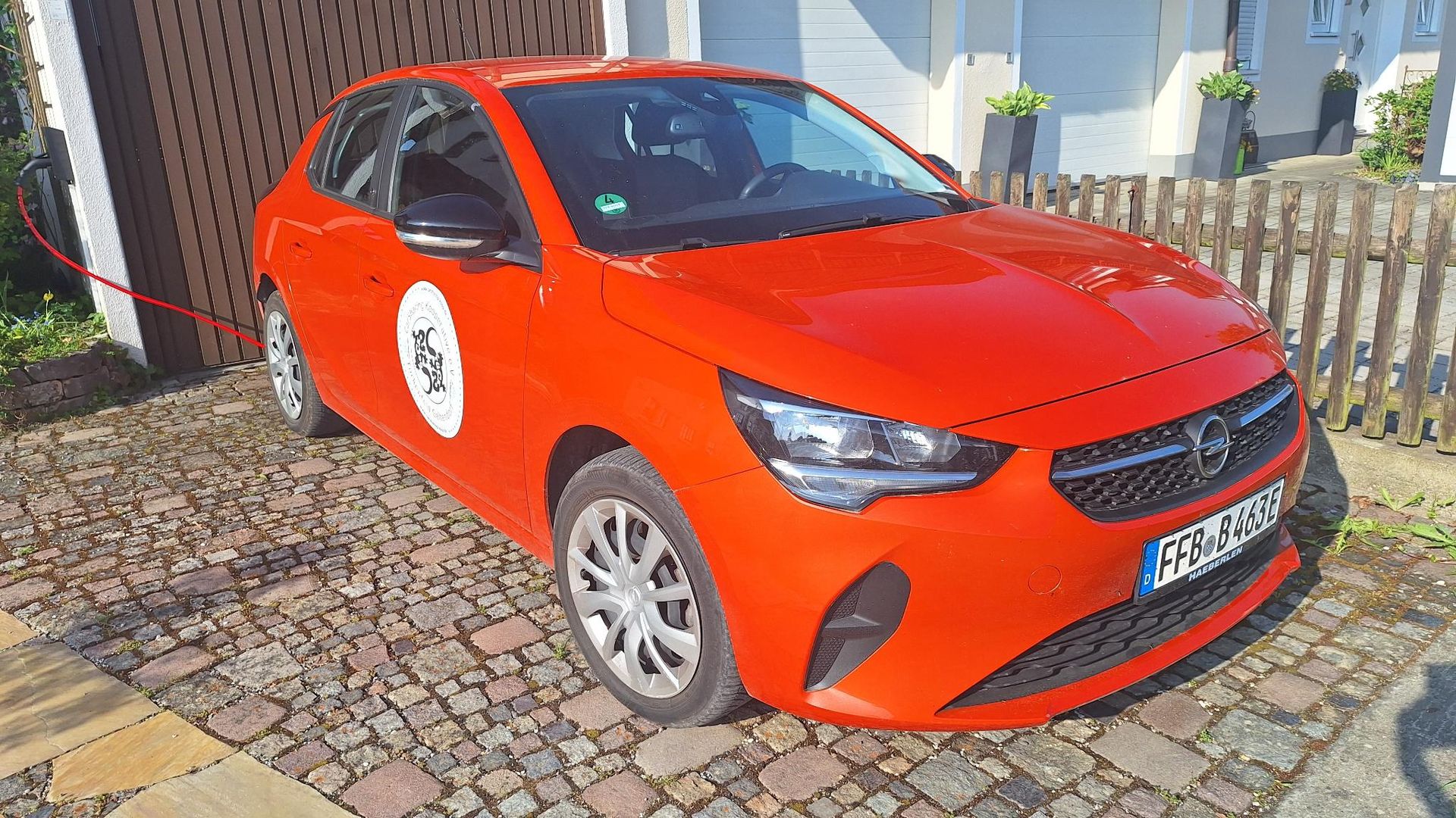 Unser erstes Elektroauto, ein weißer Opel Corsa-e an einer Ladestation